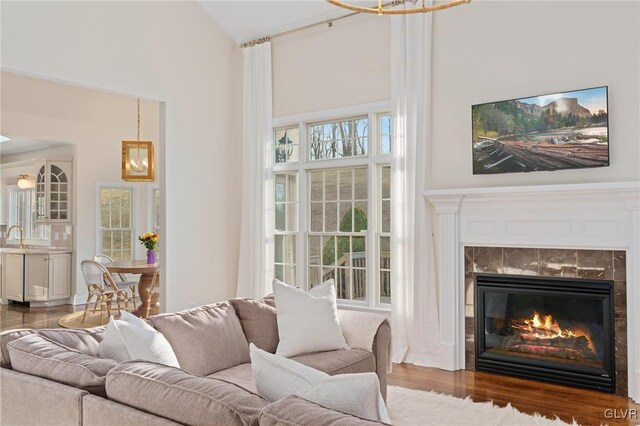 living area with a chandelier, a high ceiling, wood finished floors, and a fireplace