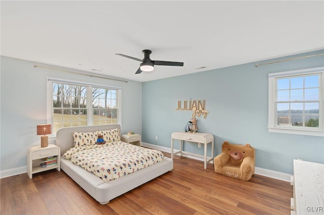 bedroom with a ceiling fan, baseboards, and wood finished floors