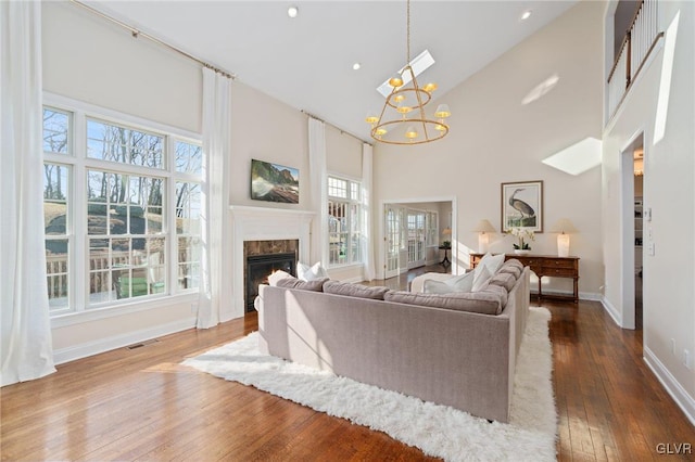 living room featuring visible vents, dark wood-type flooring, a notable chandelier, high vaulted ceiling, and a premium fireplace