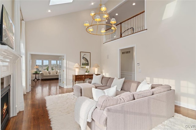 living room featuring visible vents, baseboards, a chandelier, a warm lit fireplace, and wood finished floors