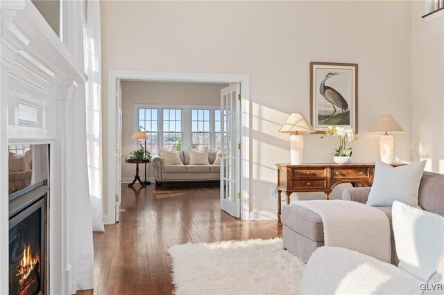 living area with baseboards, a high ceiling, hardwood / wood-style floors, and a fireplace