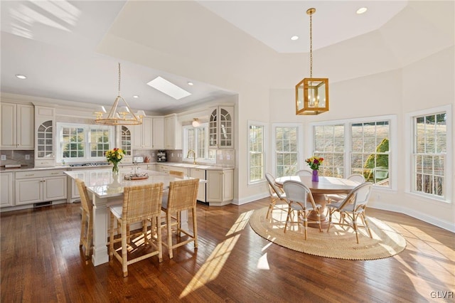 dining space featuring an inviting chandelier, plenty of natural light, dark wood-type flooring, and a raised ceiling