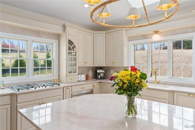 kitchen featuring light stone counters, a sink, an inviting chandelier, and stainless steel gas stovetop