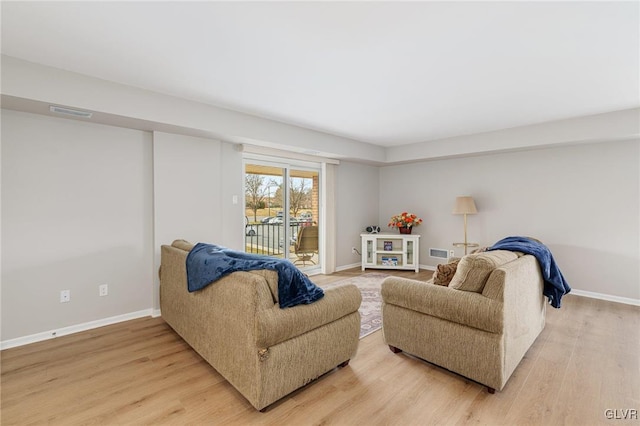 living room with visible vents, light wood-style flooring, and baseboards