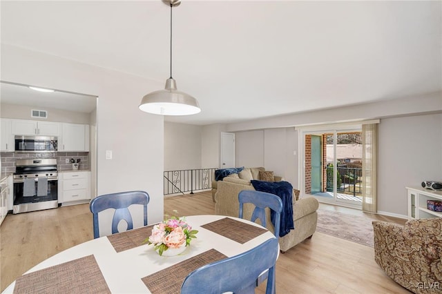 dining area featuring light wood-style floors and visible vents