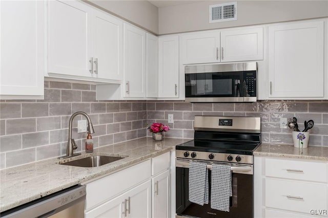 kitchen with a sink, stainless steel appliances, visible vents, and decorative backsplash