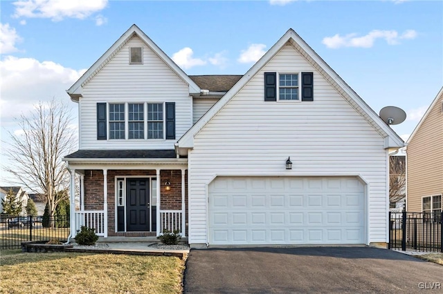 traditional-style home featuring covered porch, driveway, and fence