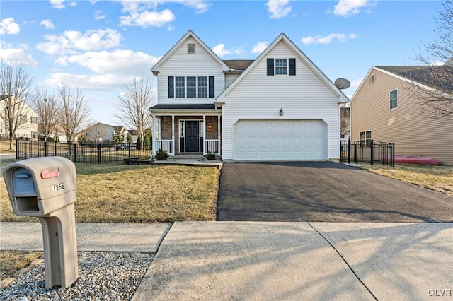 traditional home with aphalt driveway, covered porch, a front lawn, and fence