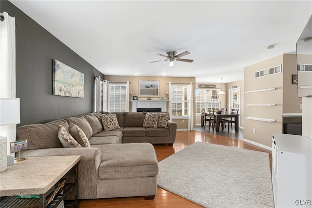 living area with visible vents, baseboards, wood finished floors, and a ceiling fan