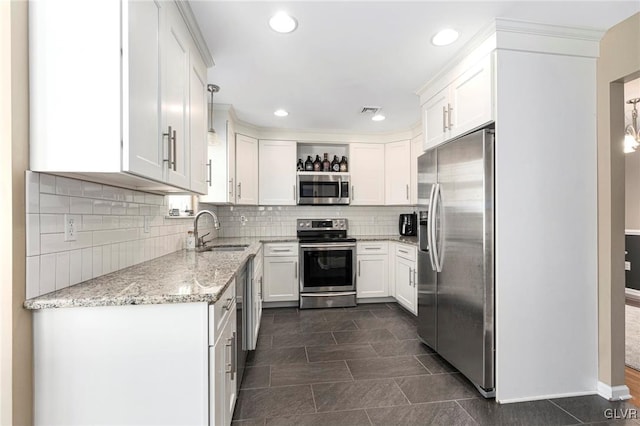 kitchen featuring a sink, stainless steel appliances, white cabinets, decorative backsplash, and light stone countertops