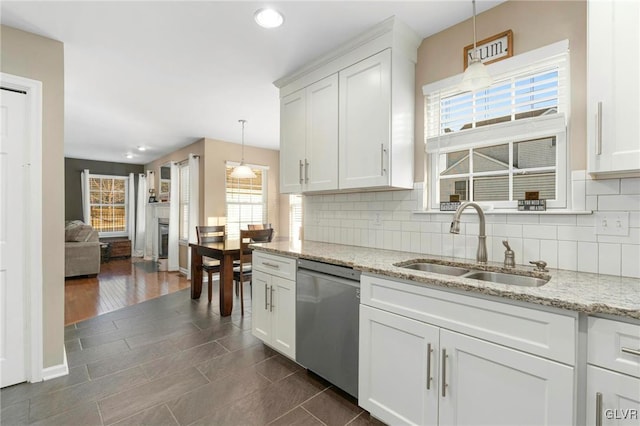 kitchen with a sink, tasteful backsplash, dishwasher, and white cabinets