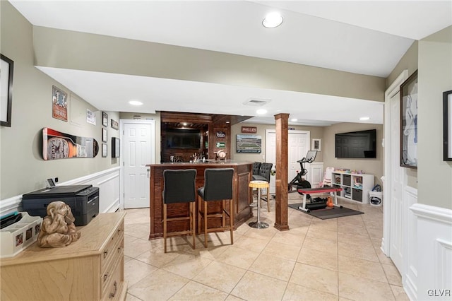 living room featuring light tile patterned floors, recessed lighting, indoor bar, and decorative columns