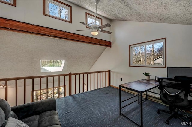 carpeted office with high vaulted ceiling, a textured ceiling, a skylight, and a ceiling fan