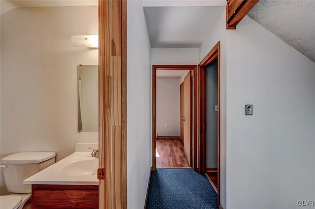 corridor featuring carpet floors, vaulted ceiling with beams, and a sink