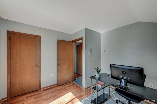 home office featuring baseboards, light wood-style floors, and vaulted ceiling