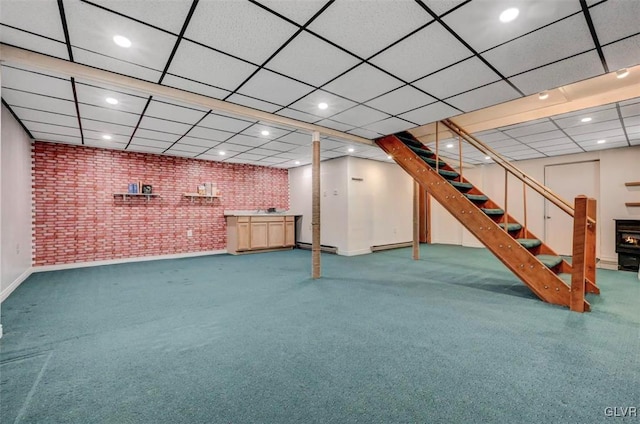 finished basement with stairway, recessed lighting, a paneled ceiling, and brick wall