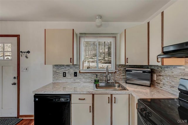 kitchen featuring decorative backsplash, black appliances, light countertops, and a sink