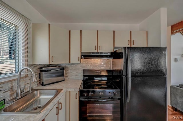 kitchen featuring black appliances, a sink, under cabinet range hood, backsplash, and light countertops