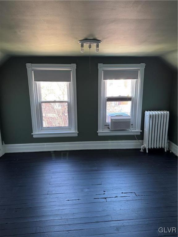 bonus room featuring lofted ceiling, cooling unit, radiator, baseboards, and dark wood-style flooring