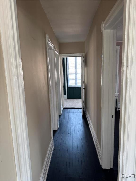 hallway with dark wood finished floors and baseboards