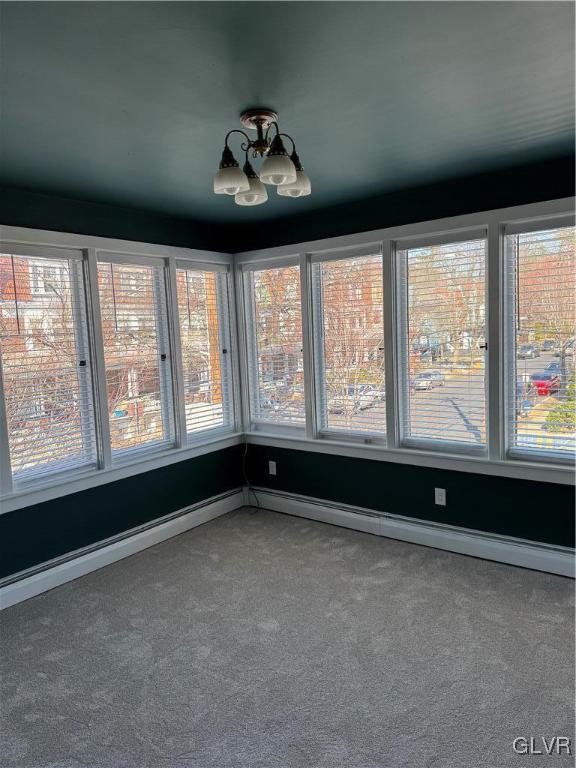 unfurnished sunroom featuring a notable chandelier and baseboard heating