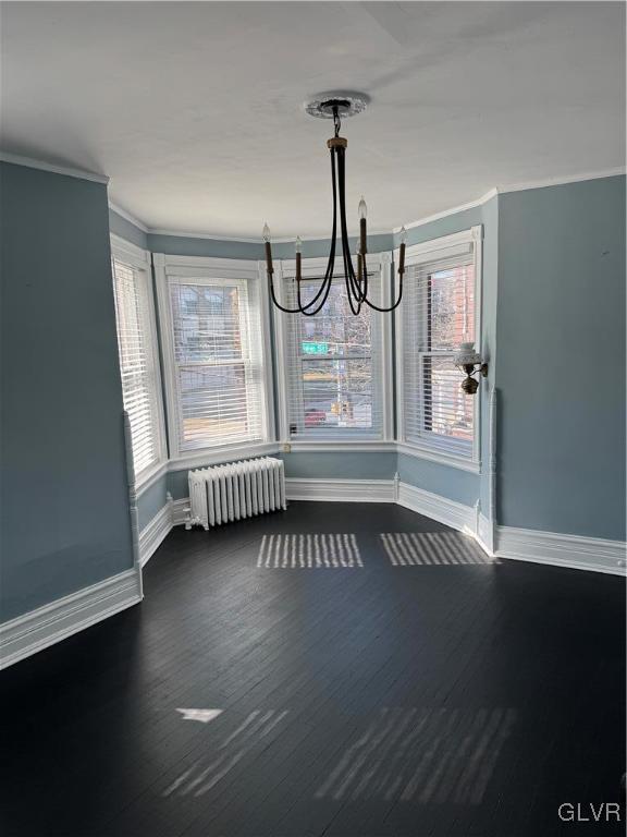 unfurnished dining area with a chandelier, a healthy amount of sunlight, crown molding, and radiator heating unit