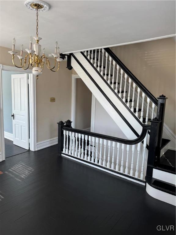 stairs with baseboards, an inviting chandelier, and wood finished floors