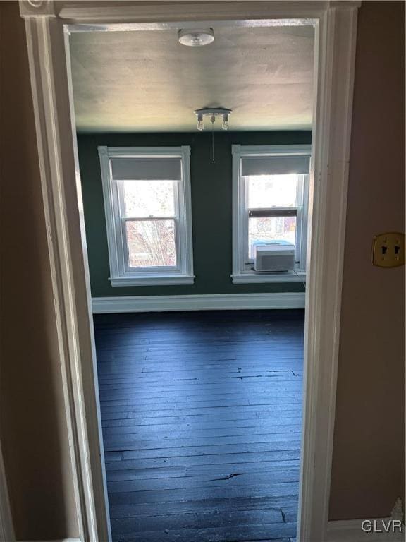 unfurnished room with hardwood / wood-style flooring, cooling unit, and baseboards