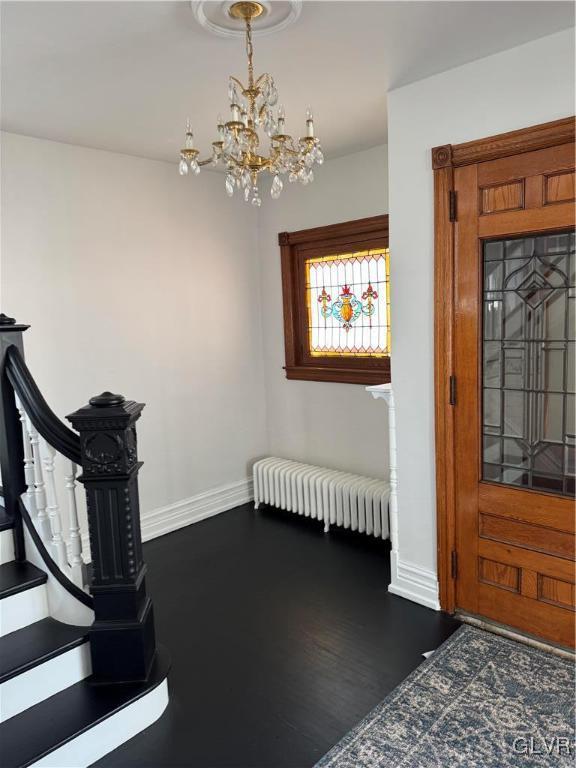 entryway with an inviting chandelier, radiator, baseboards, and dark wood-type flooring