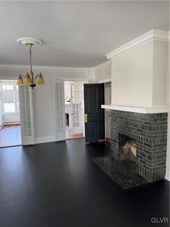 unfurnished living room featuring baseboards, dark wood-type flooring, an inviting chandelier, and crown molding