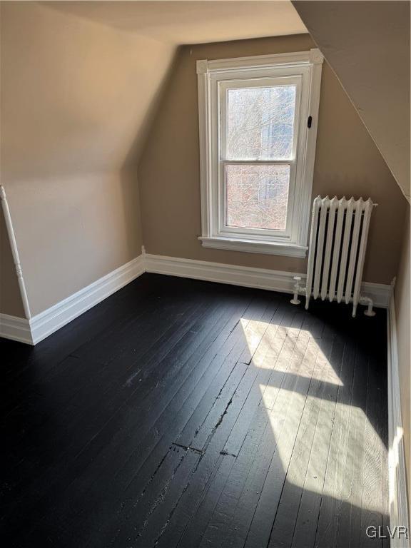 bonus room featuring baseboards, radiator heating unit, lofted ceiling, and dark wood-style flooring