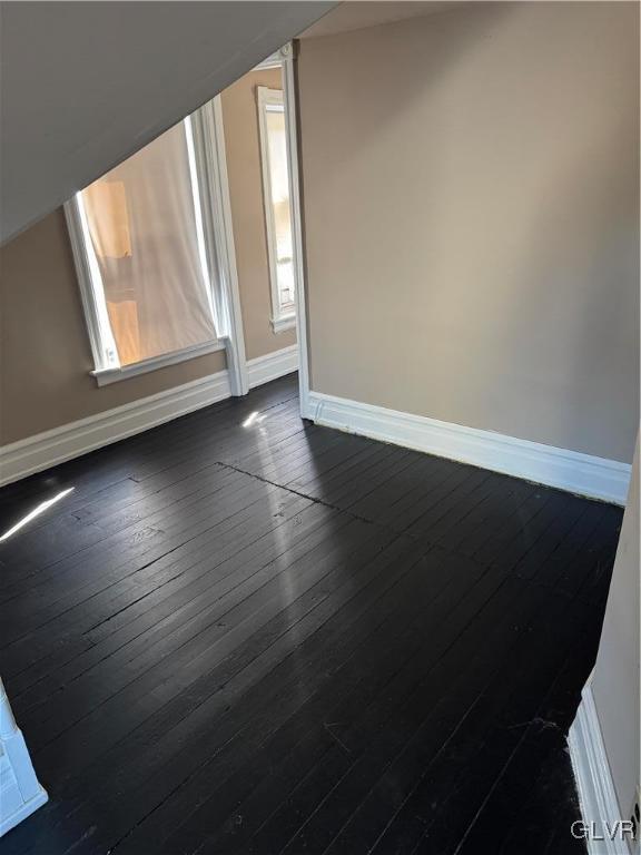 empty room with dark wood finished floors and baseboards