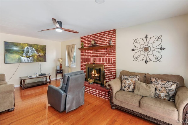 living room featuring baseboards, a fireplace, wood finished floors, and a ceiling fan