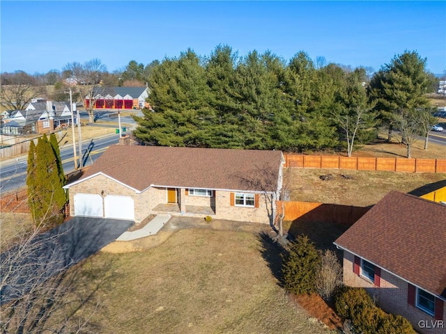 view of front facade featuring aphalt driveway, an attached garage, fence, and a front yard