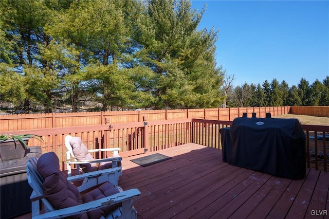 wooden deck featuring a fenced backyard and a grill