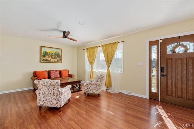 foyer entrance featuring visible vents, ceiling fan, baseboards, and wood finished floors