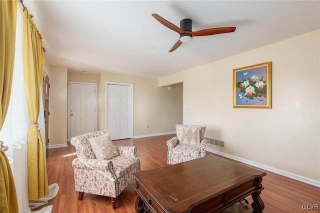 sitting room featuring a ceiling fan, wood finished floors, baseboards, and visible vents