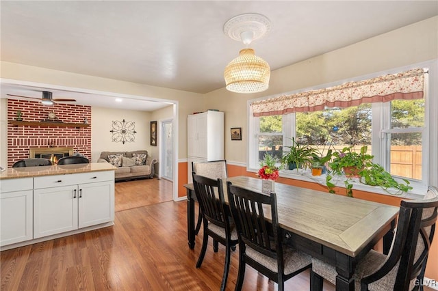 dining space featuring light wood-style flooring and a brick fireplace