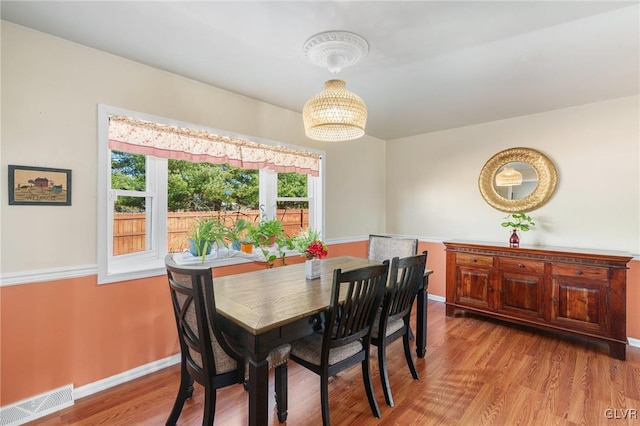 dining space with a notable chandelier, wood finished floors, visible vents, and baseboards