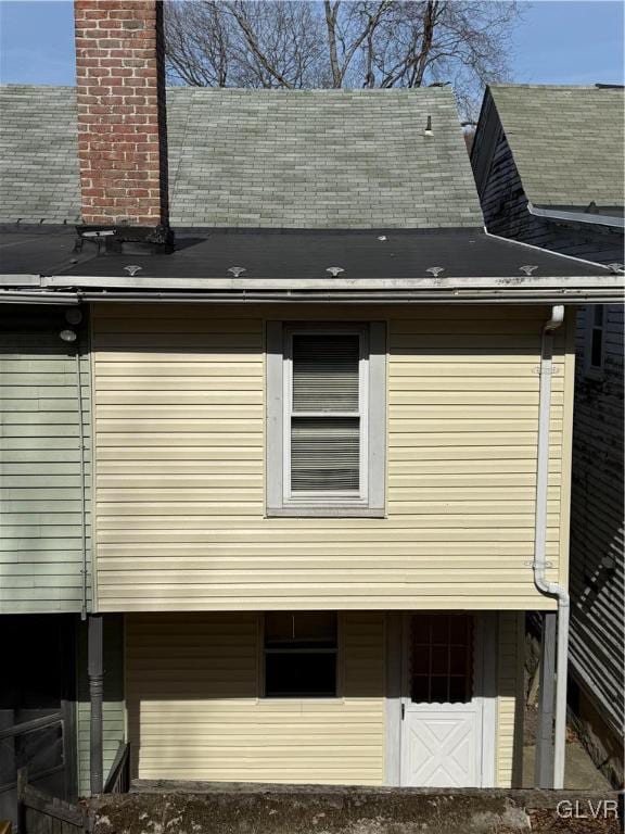 view of side of property featuring roof with shingles and a chimney