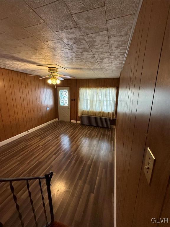 unfurnished living room featuring ceiling fan, baseboards, radiator, and wood finished floors