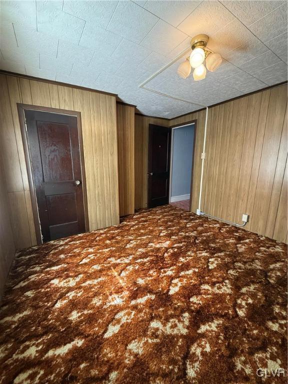 carpeted empty room with wood walls