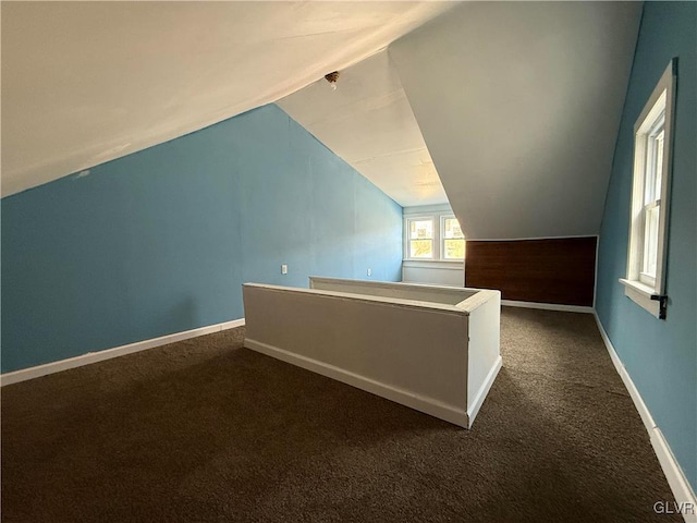 additional living space with lofted ceiling, baseboards, and dark colored carpet