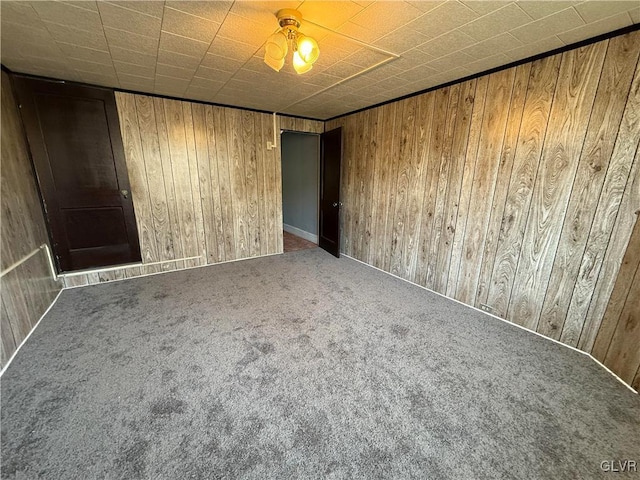 unfurnished room featuring carpet flooring and wooden walls