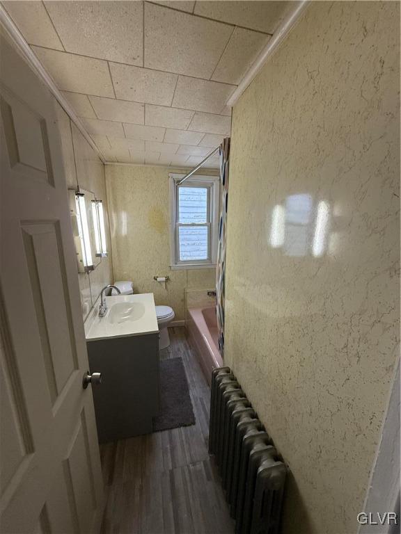 full bathroom with toilet, shower / bath combination, radiator heating unit, wood finished floors, and vanity