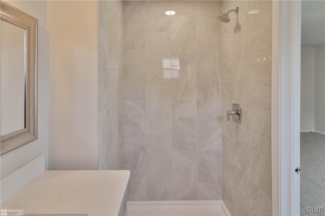 full bath with a tile shower and vanity