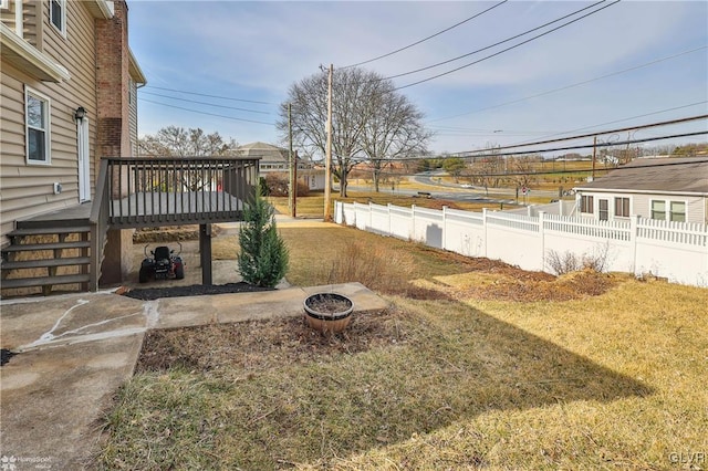 view of yard featuring a deck, a patio area, a fire pit, and fence