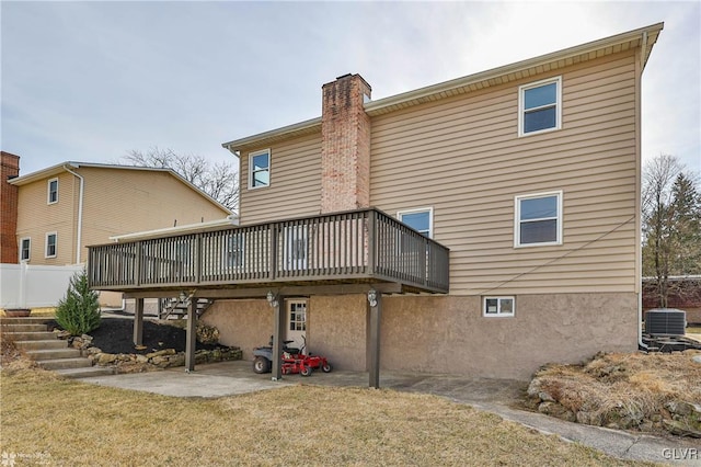 back of house with stairway, a yard, a chimney, a deck, and central air condition unit