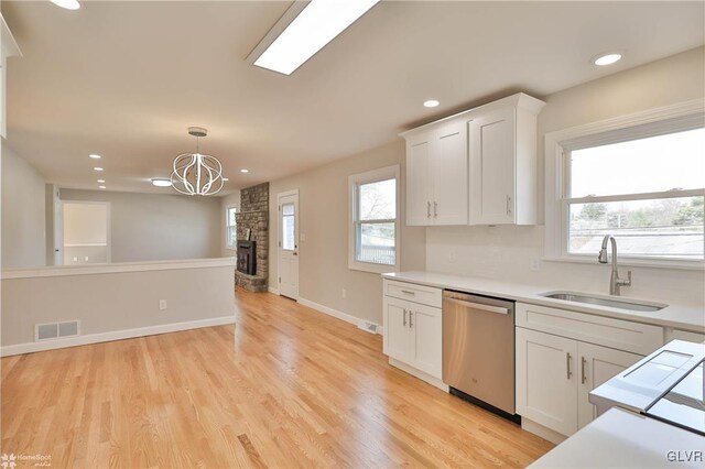 kitchen with visible vents, a wealth of natural light, stainless steel dishwasher, white cabinetry, and a sink