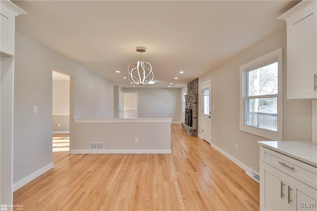 interior space featuring light wood finished floors, visible vents, and white cabinets